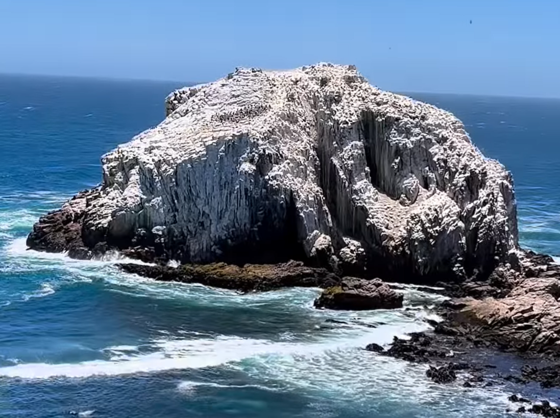 Peña Blanca frente a la costa de Algarrobo, islote rocoso poblado de aves marinas rodeado por el océano