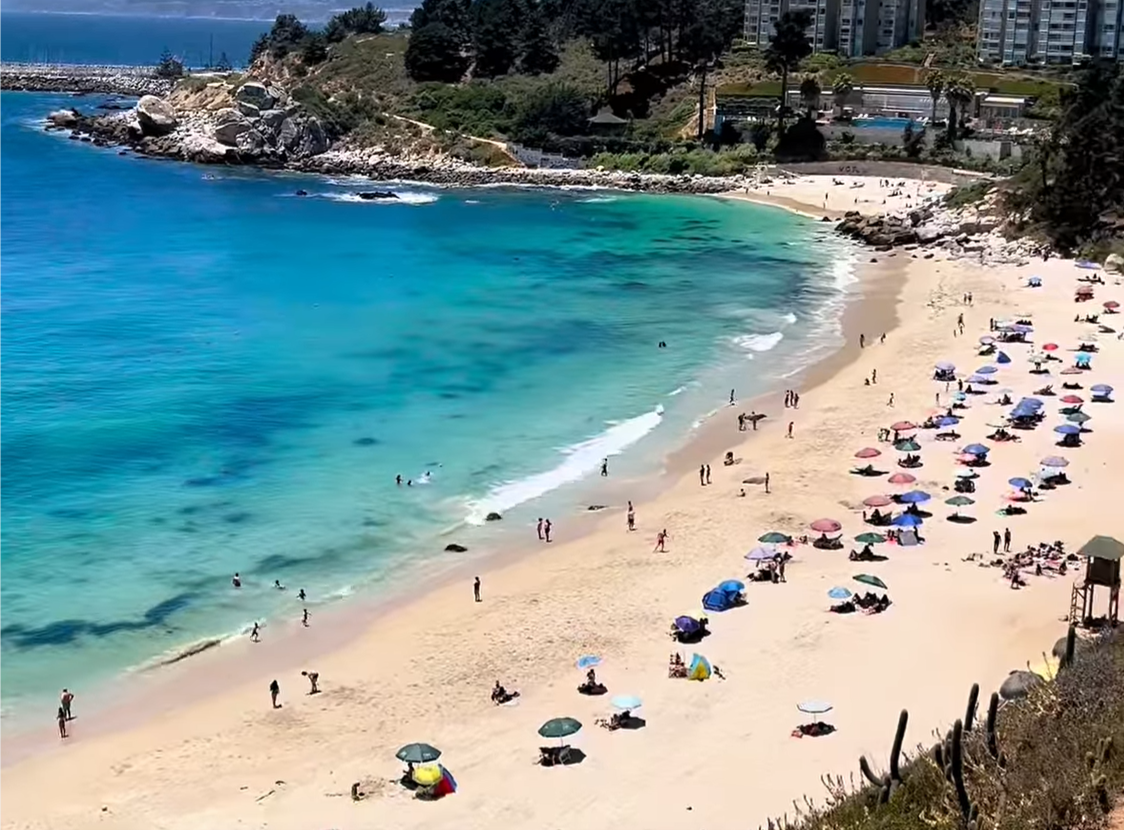Playa principal de Algarrobo: arena dorada, mar turquesa y quitasoles de bañistas en un día soleado
